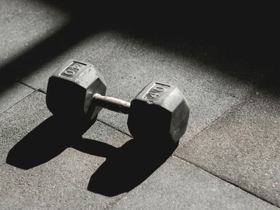 Black heavy dumbbells on a dark rubber gym floor